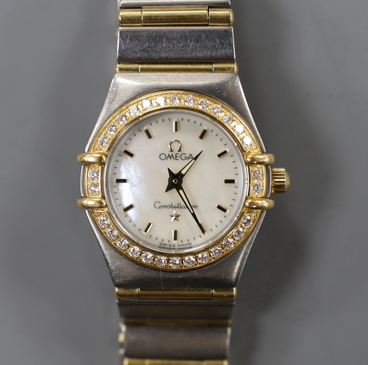 A lady's modern steel and yellow metal Omega Constellation quartz wrist watch and bracelet, with mother of pearl dial and diamond set bezel, with box and some papers, including precious gem certificate